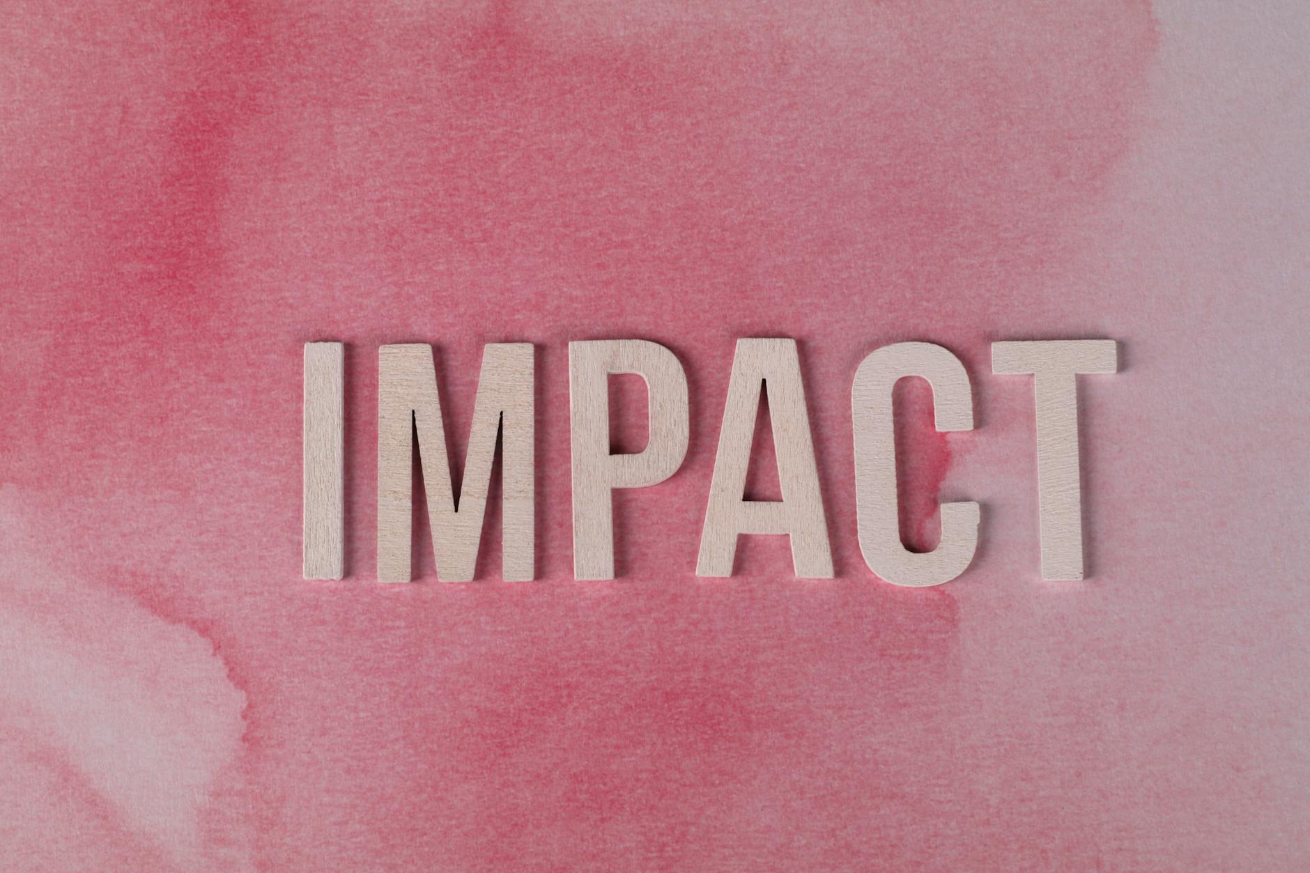 wooden letters forming impact on pink background